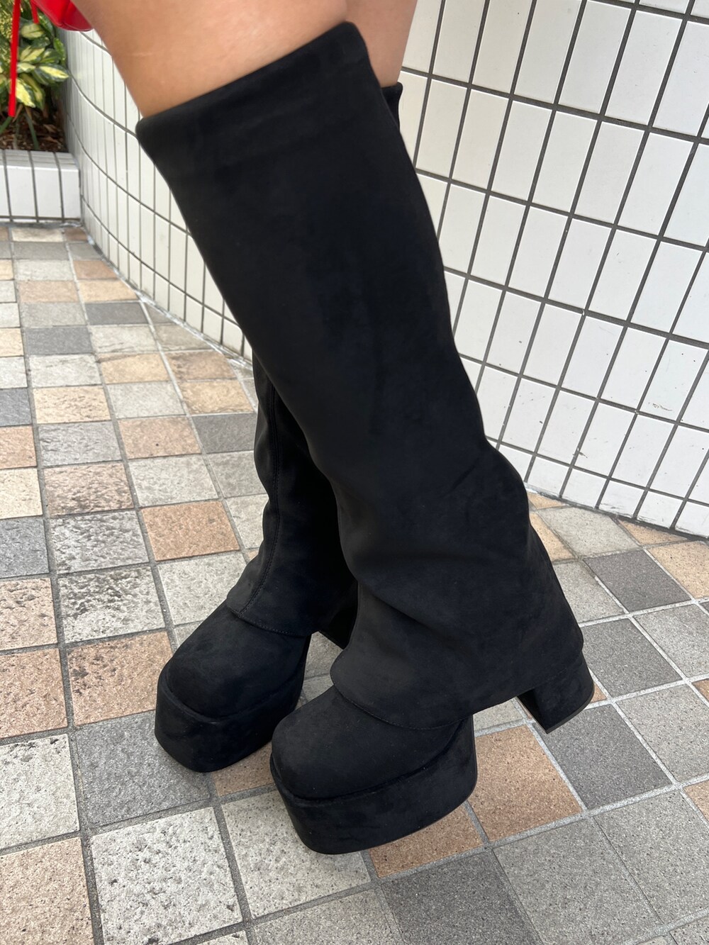 レッド系のスウェット、ブラック系のハンドバッグ、ブラック系のブーツを着用したレディースの秋コーディネートの6枚目の写真