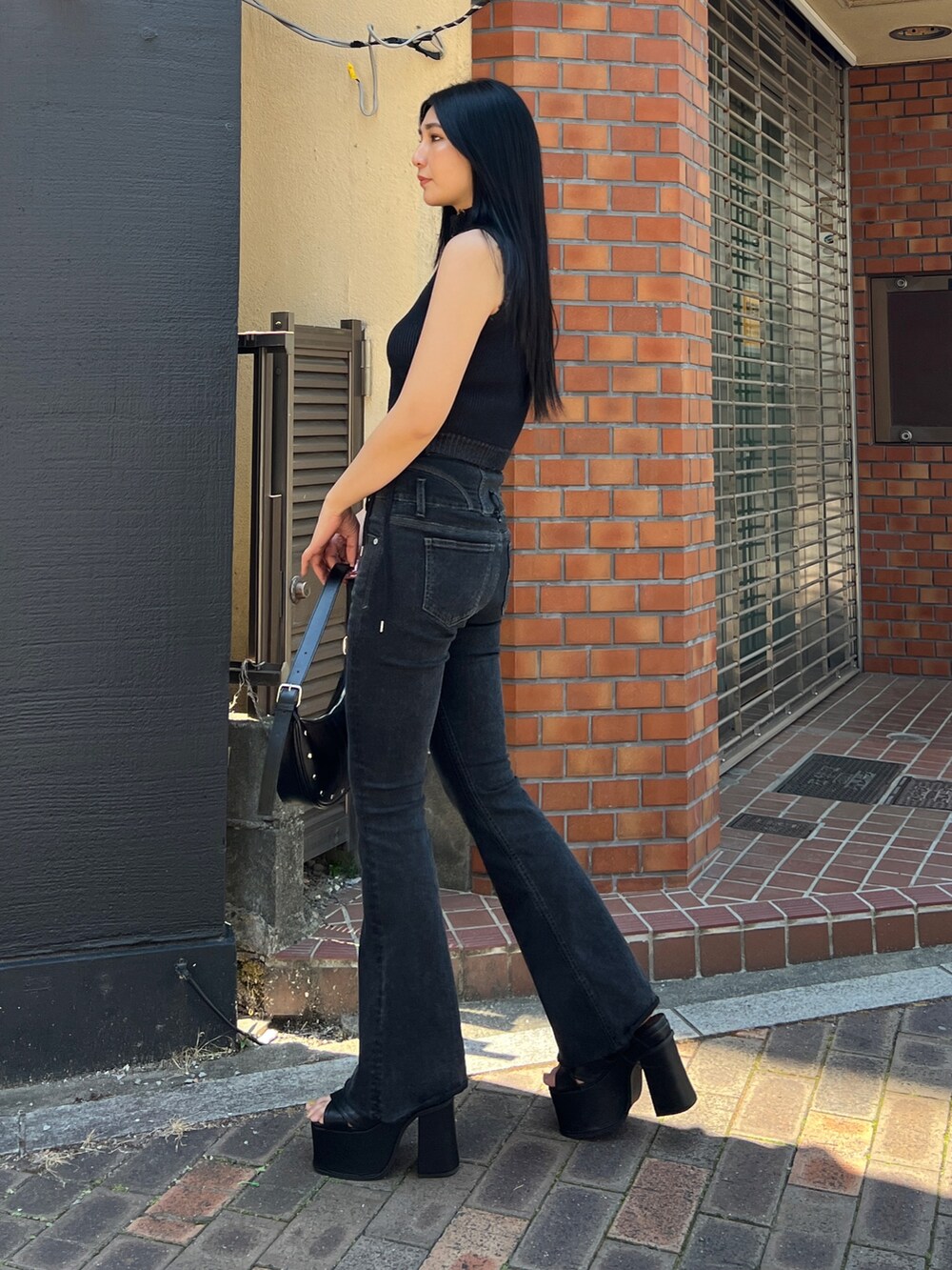 ブラック系のタンクトップ、ブラック系のデニムパンツ、ブラック系のサンダルを着用したレディースの春コーディネートの2枚目の写真