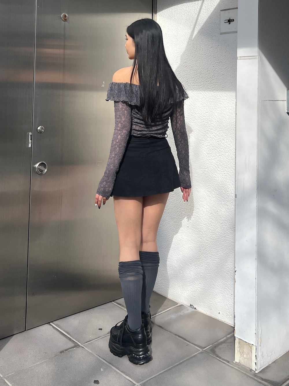 グレー系のTシャツ/カットソー、ブラック系のスカート、その他のスニーカーを着用したレディースの冬コーディネートの3枚目の写真