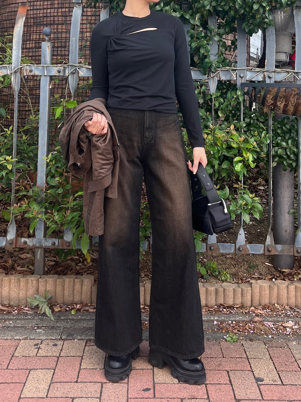 ブラック系のデニムパンツ、ブラック系のブーツ、ブラック系のTシャツ/カットソーを着用したレディースの春コーディネートの3枚目の写真