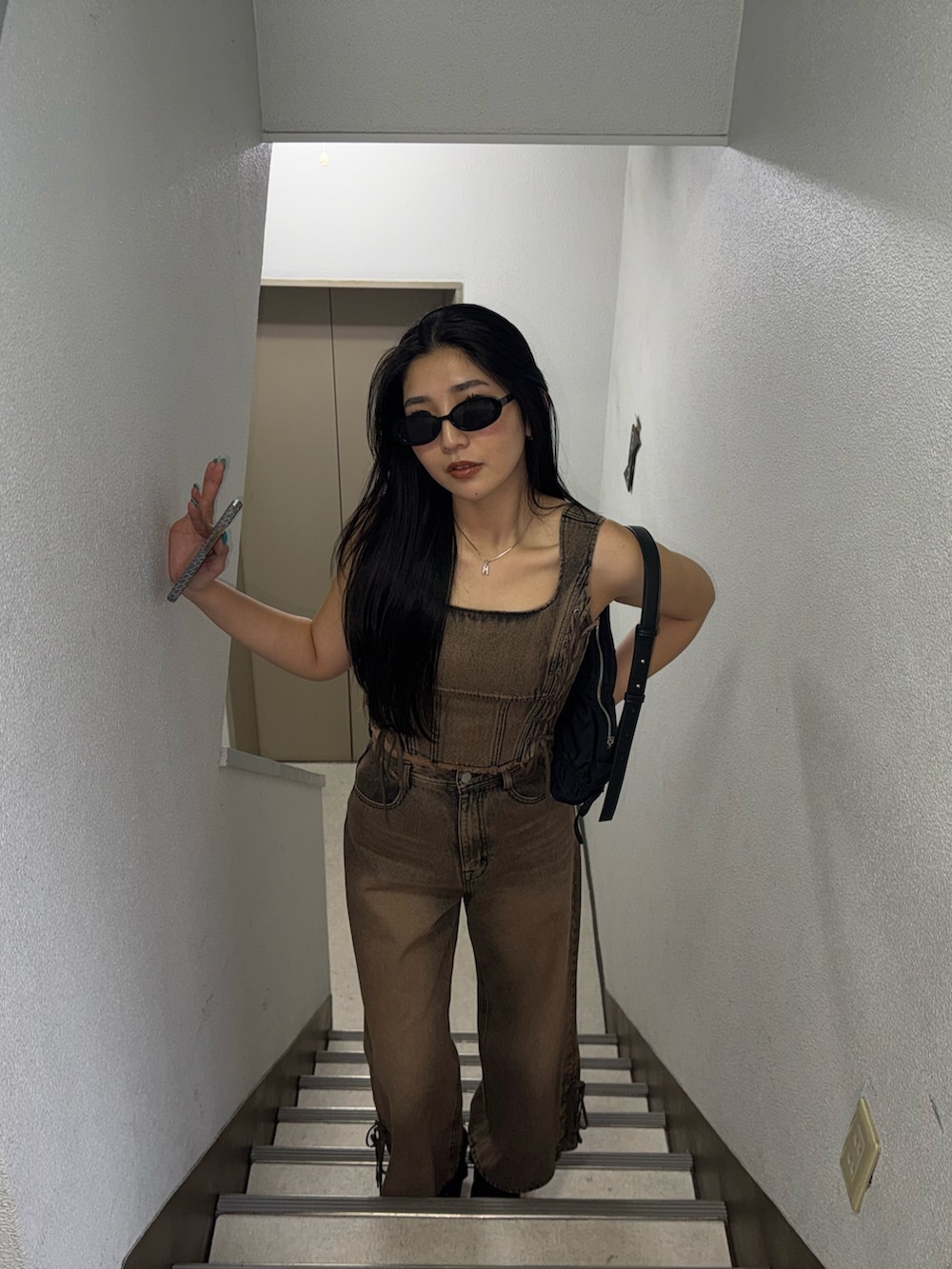 ブラウン系のデニムパンツ、ブラウン系のタンクトップ、ブラック系のスニーカーを着用したレディースの春コーディネートの3枚目の写真