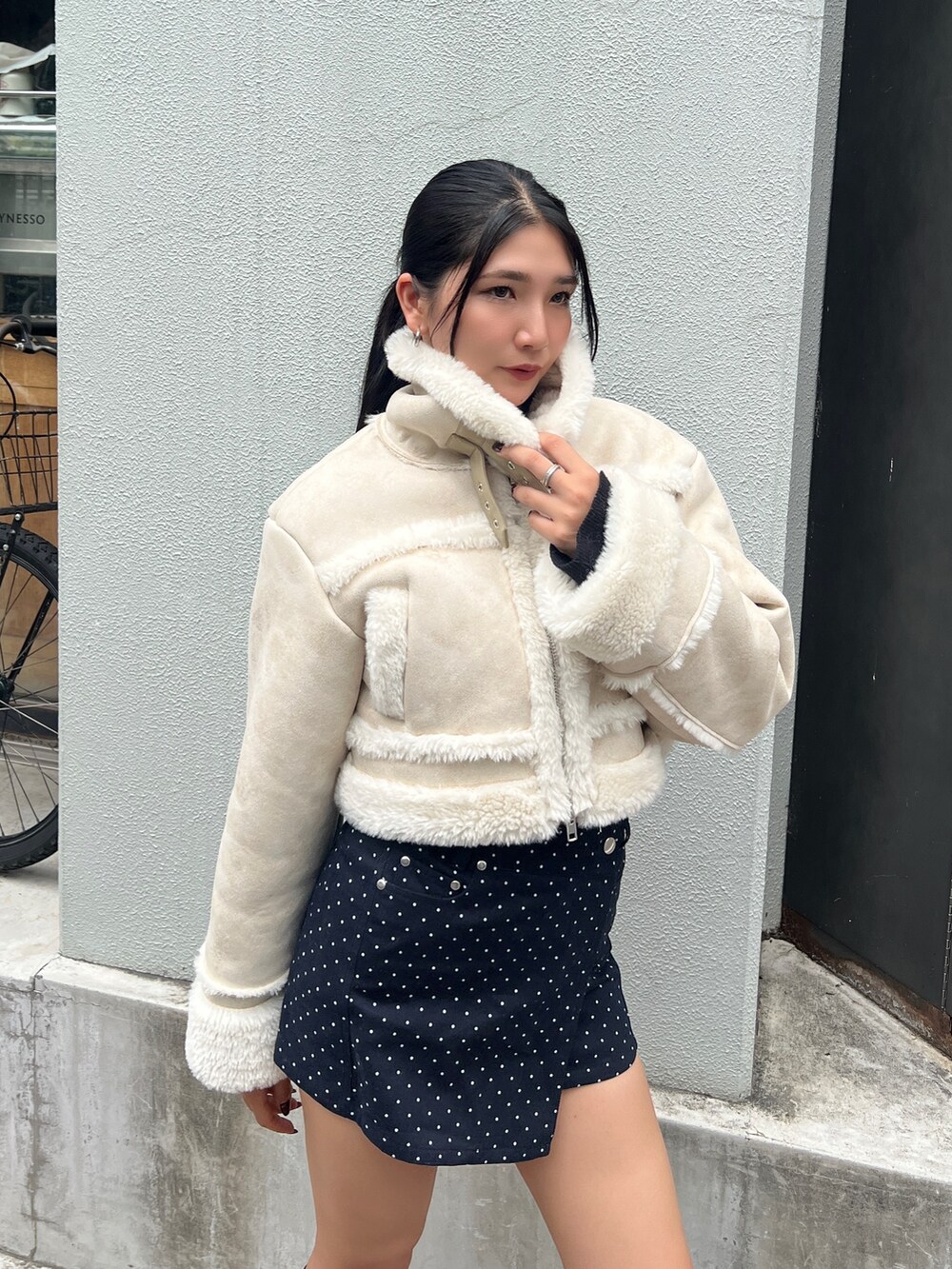 ホワイト系のブルゾン、ブルー系のスカート、ブラック系のブーツを着用したレディースの秋コーディネートの3枚目の写真