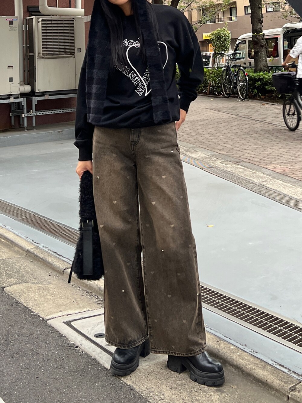 ブラック系のスウェット、ブラウン系のデニムパンツ、ブラック系のブーツを着用したレディースの秋コーディネートの2枚目の写真