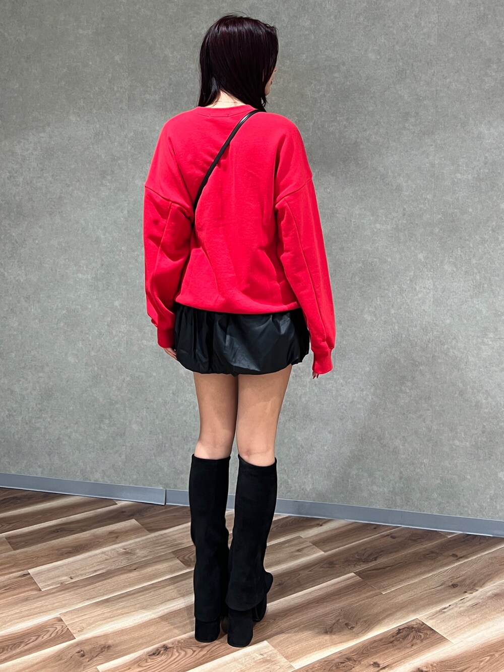 レッド系のスウェット、ブラック系のハンドバッグ、ブラック系のブーツを着用したレディースの秋コーディネートの3枚目の写真