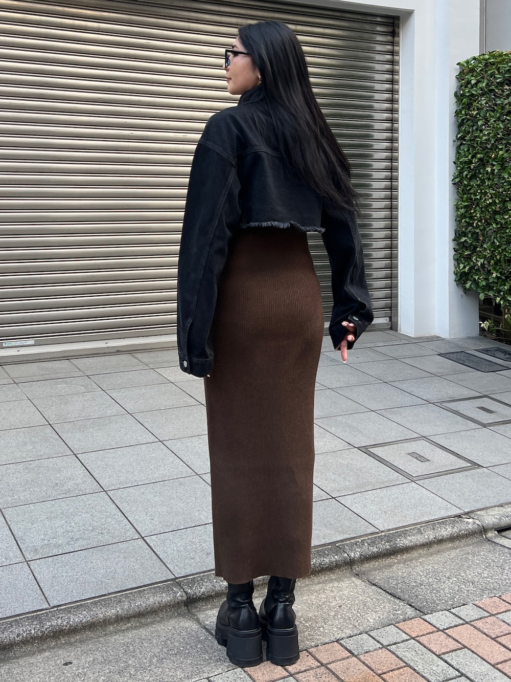 ブラック系のデニムジャケット、ブラウン系のワンピース、ブラック系のブーツを着用したレディースの夏コーディネートの2枚目の写真