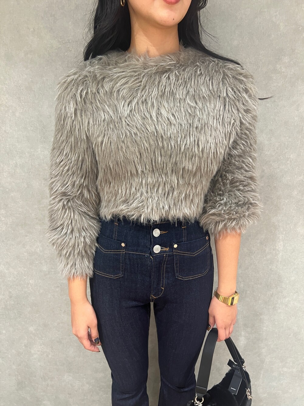 グレー系のニット/セーター、ブルー系のデニムパンツ、ブラック系のハンドバッグを着用したレディースの秋コーディネートの5枚目の写真