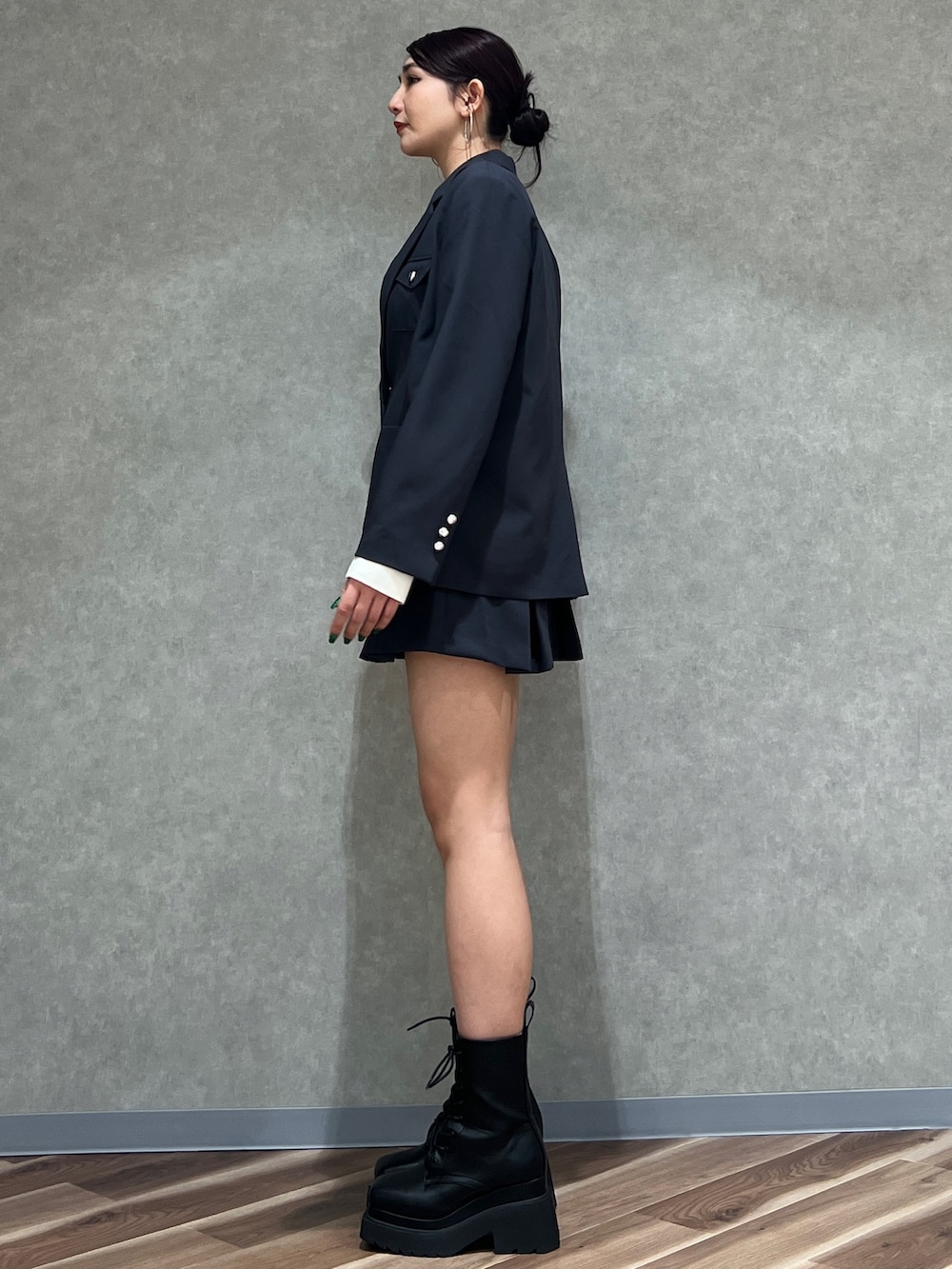 グレー系のテーラードジャケット、ホワイト系のニット/セーター、グレー系のスカートを着用したレディースの冬コーディネートの2枚目の写真