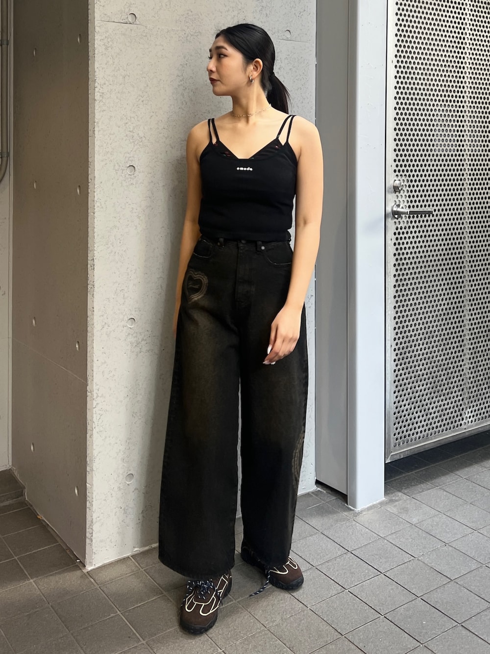 ブラック系のキャミソール、ブラック系のデニムパンツ、ブラウン系のスニーカーを着用したレディースの春コーディネートの2枚目の写真
