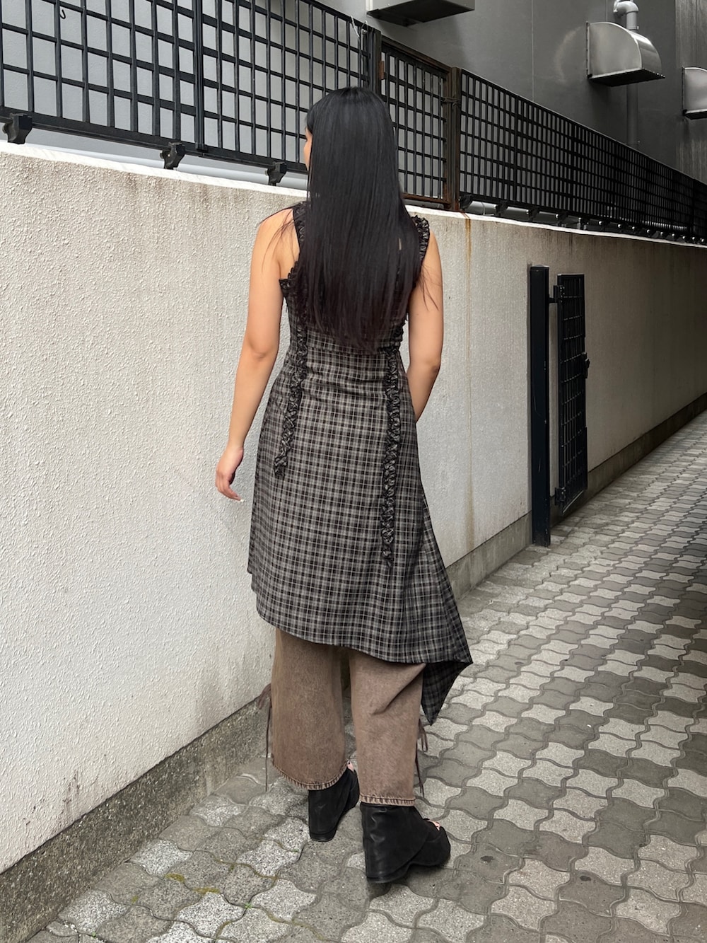 ブラック系のワンピース、ブラウン系のデニムパンツ、ブラック系のサンダルを着用したレディースの春コーディネートの3枚目の写真