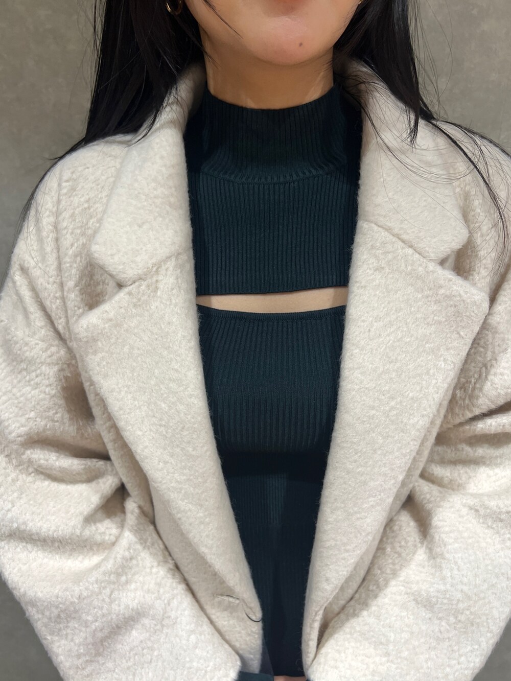 グリーン系のワンピース、ホワイト系のチェスターコート、ブラック系のハンドバッグを着用したレディースの冬コーディネートの4枚目の写真