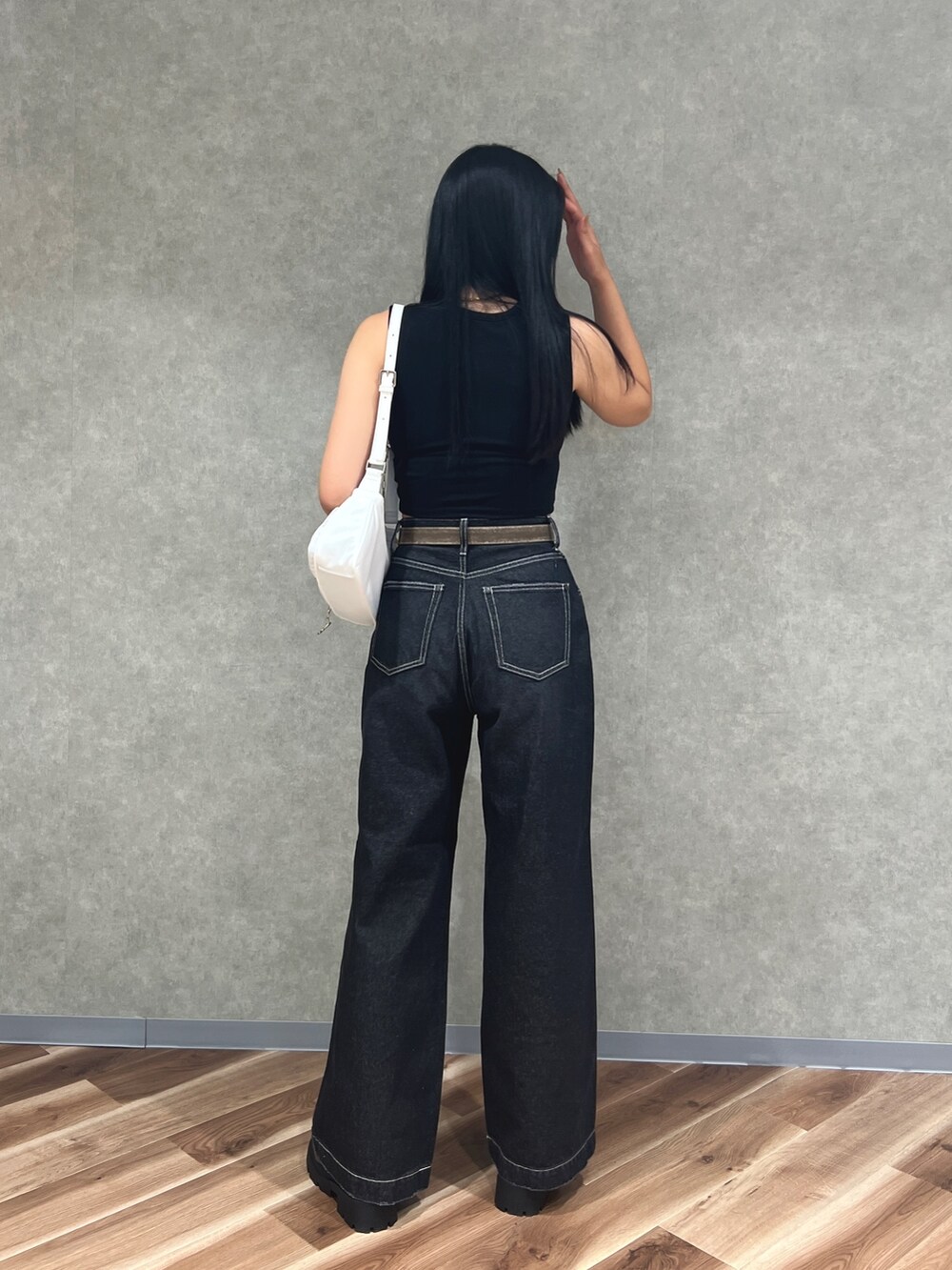 ブラック系のタンクトップ、ブルー系のデニムパンツ、ホワイト系のハンドバッグを着用したレディースの夏コーディネートの3枚目の写真