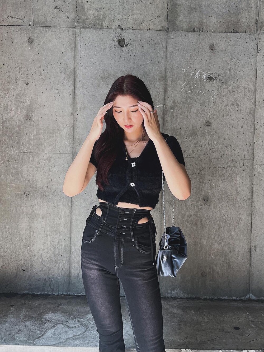 ブラック系のニット/セーター、ブラック系のデニムパンツ、グレー系のハンドバッグを着用したレディースの夏コーディネートの4枚目の写真