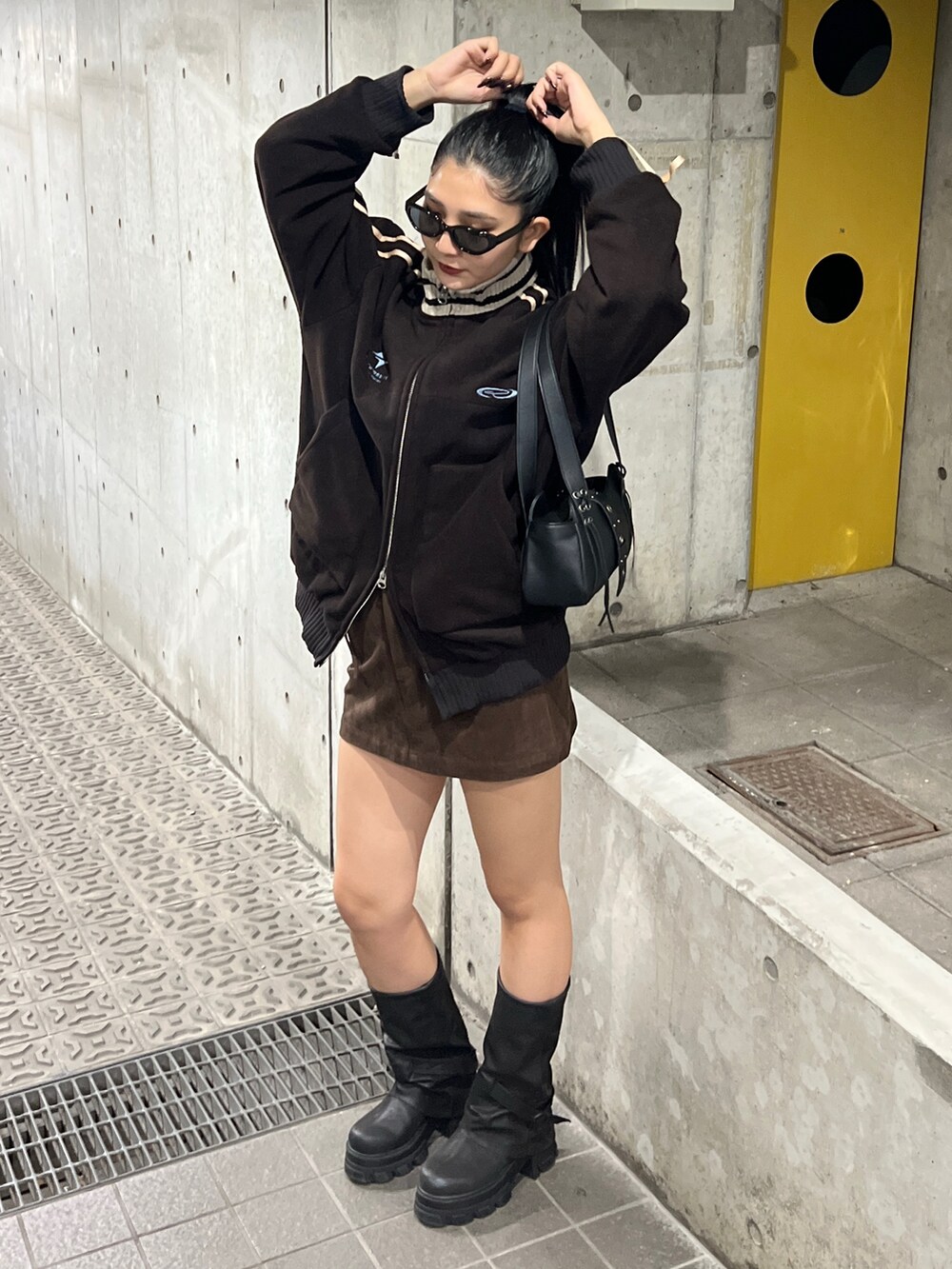 ブラウン系のブルゾン、ブラック系のブーツ、ブラウン系のスカートを着用したレディースの秋コーディネートの3枚目の写真