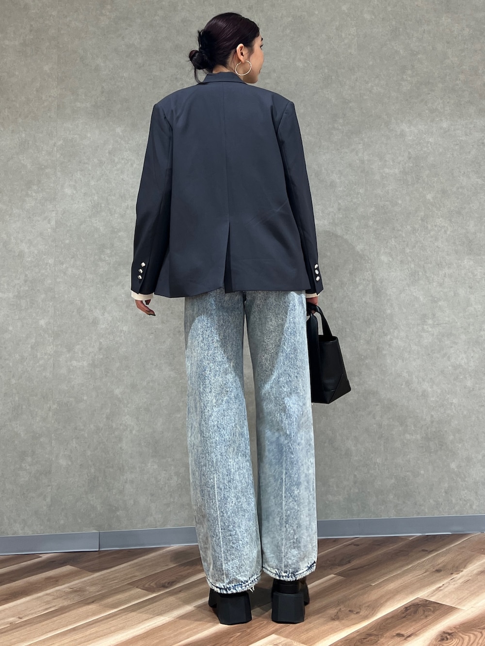 グレー系のテーラードジャケット、ブルー系のデニムパンツ、ブラック系のブーツを着用したレディースの冬コーディネートの4枚目の写真