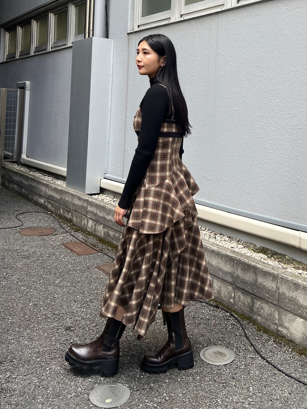 ブラック系のニット/セーター、ベージュ系のワンピース、ブラウン系のブーツを着用したレディースの冬コーディネートの2枚目の写真