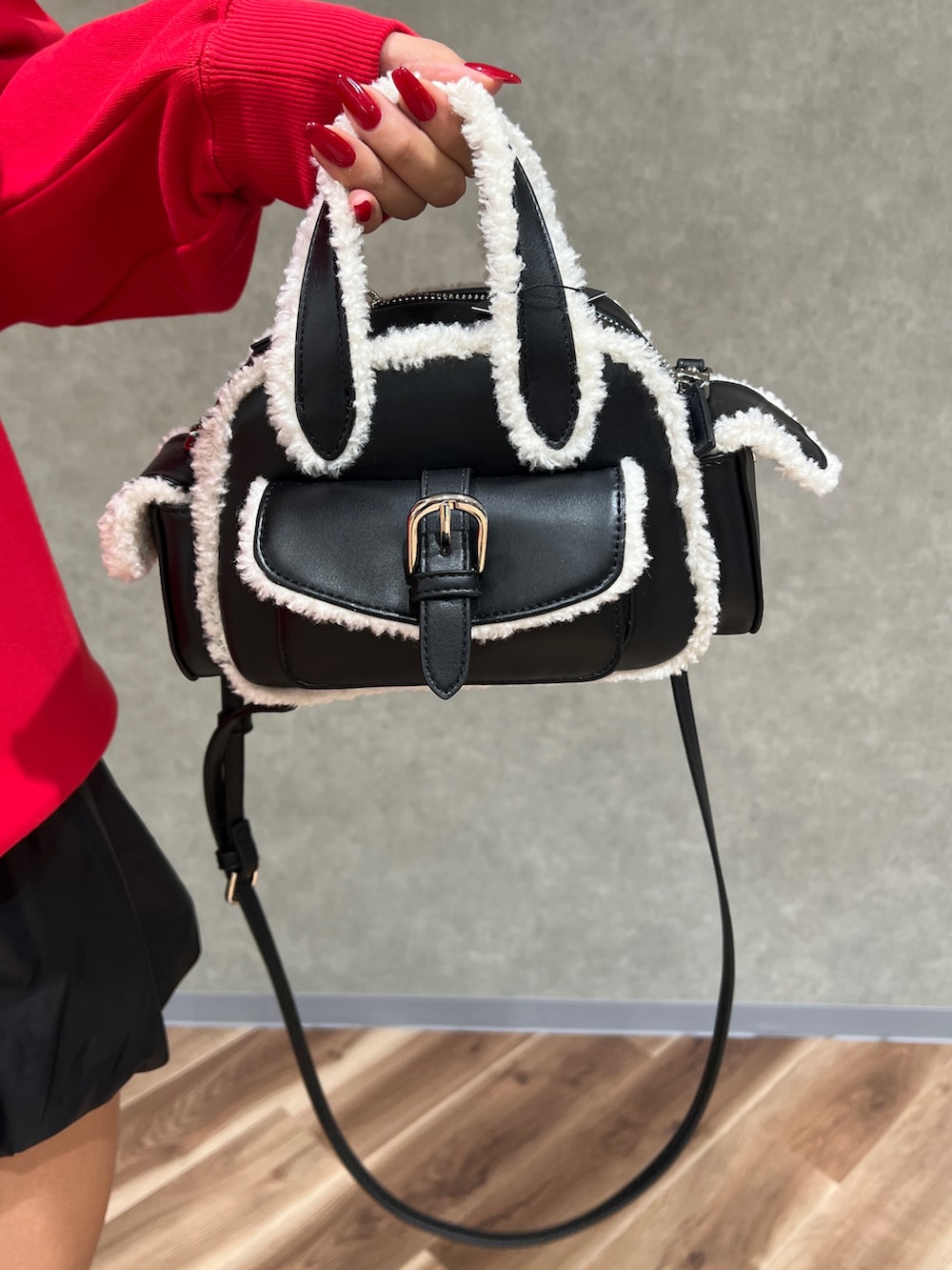 ブラック系のブーツ、ブラック系のハンドバッグ、グレー系のダウンベストを着用したレディースの秋コーディネートの6枚目の写真