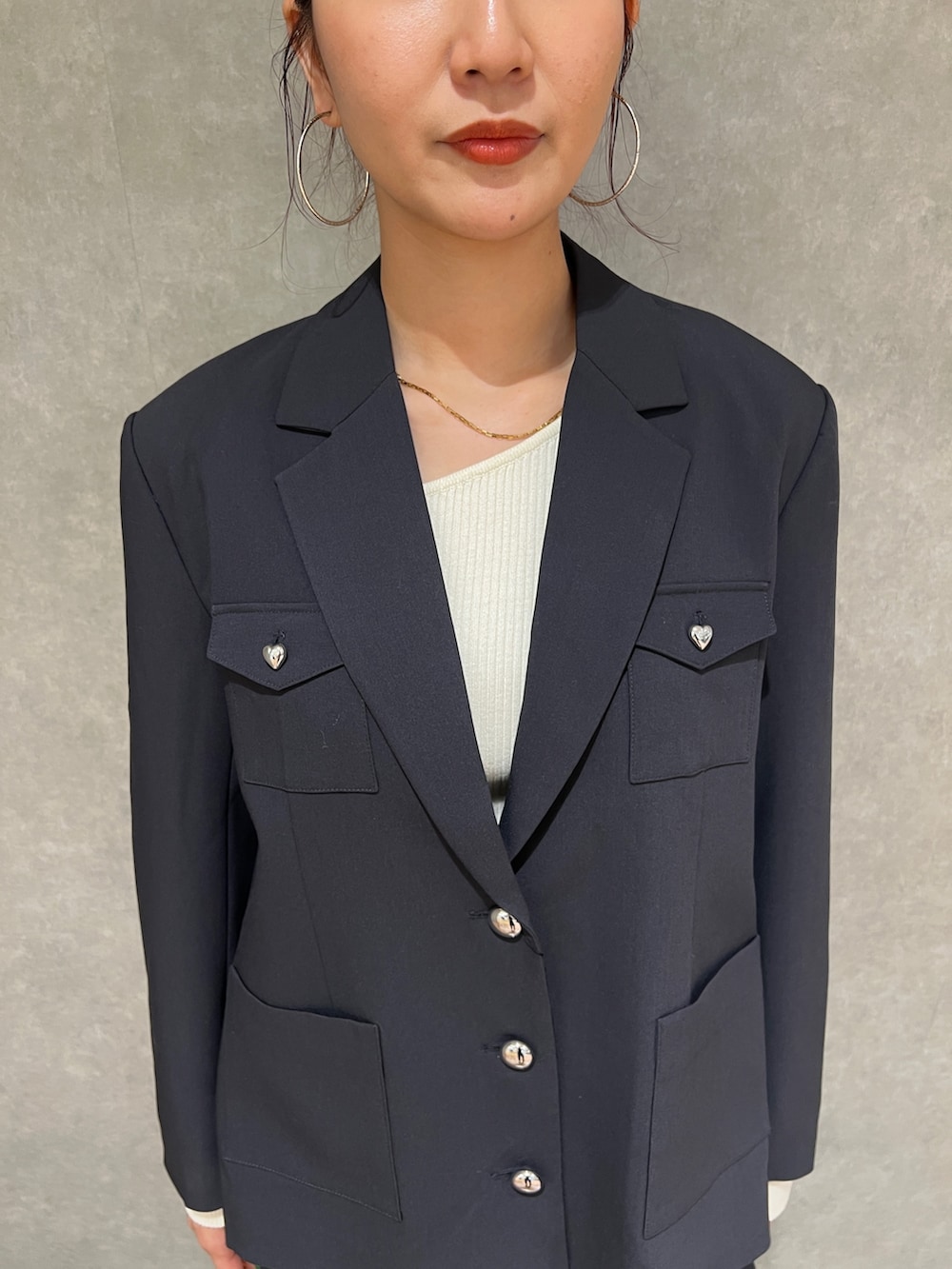 グレー系のテーラードジャケット、ホワイト系のニット/セーター、グレー系のスカートを着用したレディースの冬コーディネートの4枚目の写真