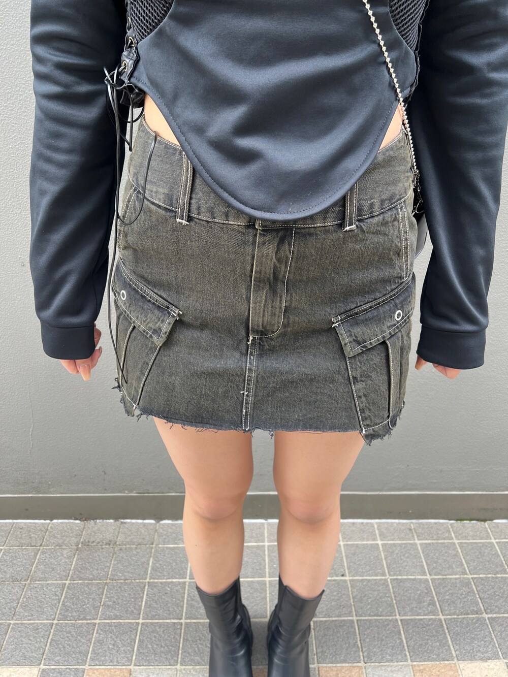 ブラック系のスカート、ブラック系のブーツ、ブラック系のハンドバッグを着用したレディースの春コーディネートの4枚目の写真