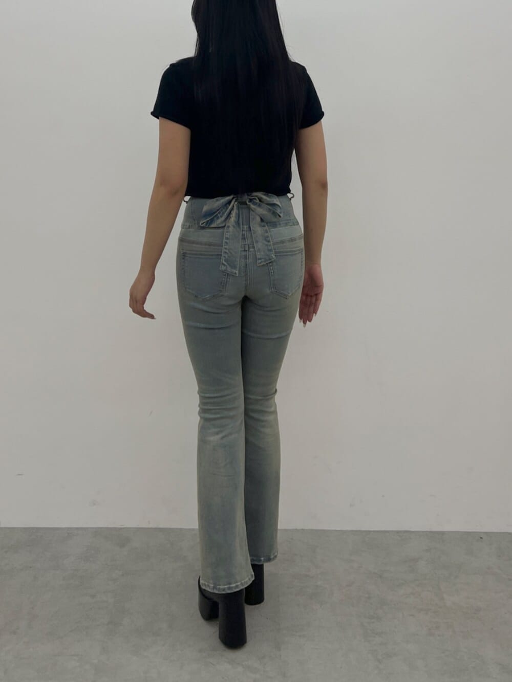 ブラック系のニット/セーター、ブルー系のデニムパンツ、ブラック系のブーツを着用したレディースの夏コーディネートの3枚目の写真