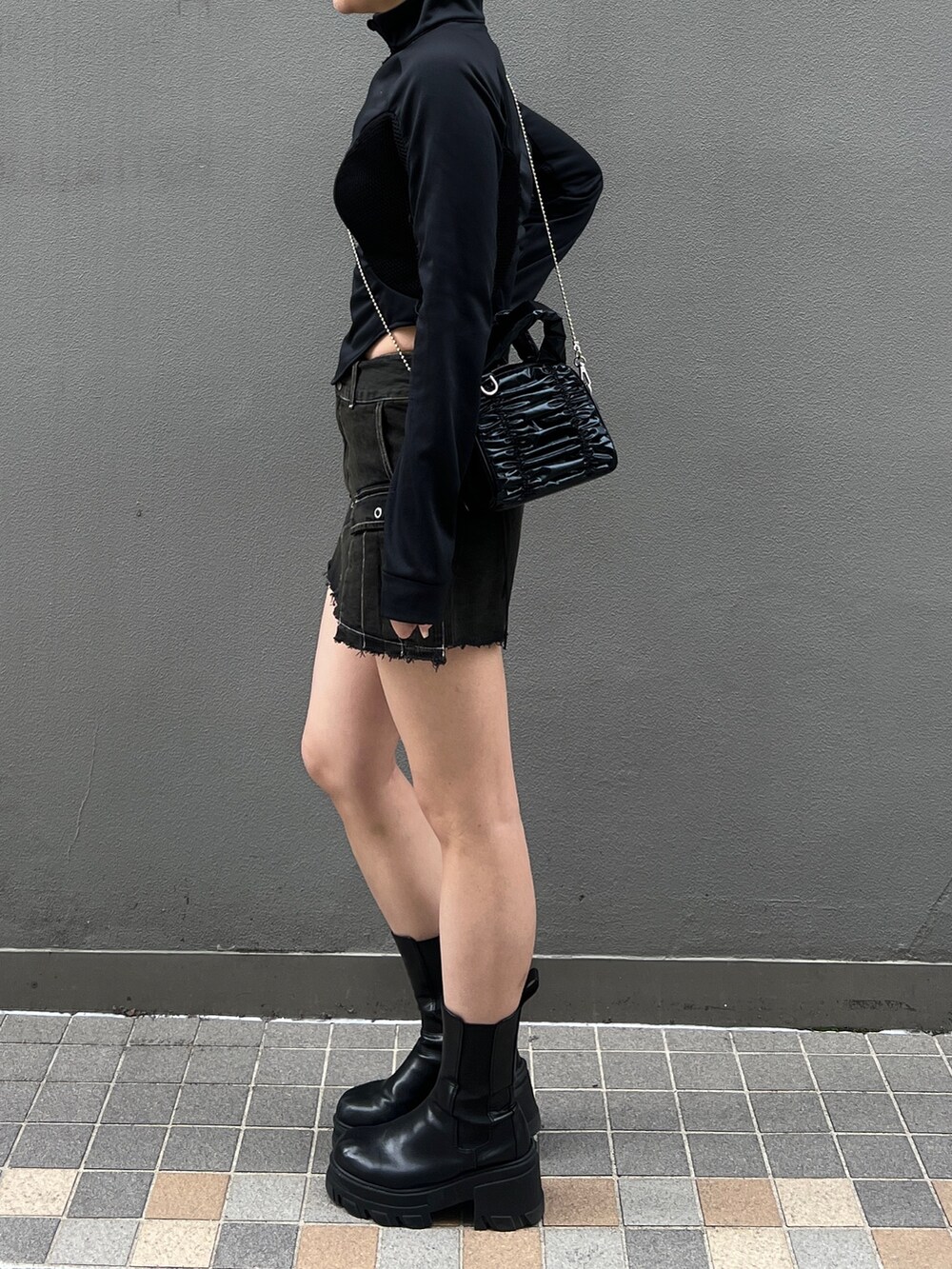 ブラック系のスカート、ブラック系のブーツ、ブラック系のハンドバッグを着用したレディースの春コーディネートの2枚目の写真