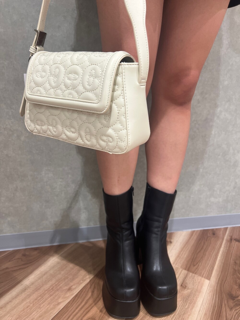 ブラック系のワンピース、ブラック系のブーツ、ホワイト系のハンドバッグを着用したレディースの秋コーディネートの6枚目の写真