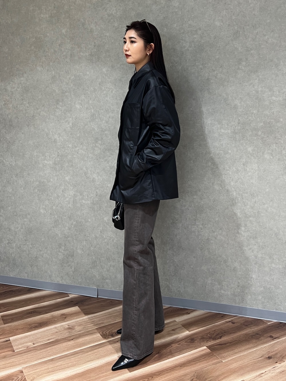 ブラック系のナイロンジャケット、ブラウン系のデニムパンツ、ブラック系のパンプスを着用したレディースの春コーディネートの2枚目の写真