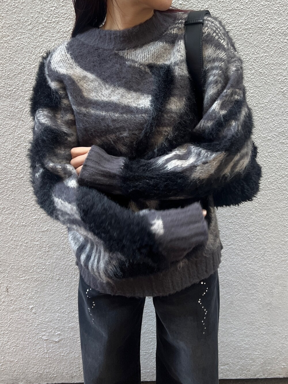 ブラック系のデニムパンツ、グレー系のニット/セーター、ブラック系のハンドバッグを着用したレディースの冬コーディネートの6枚目の写真