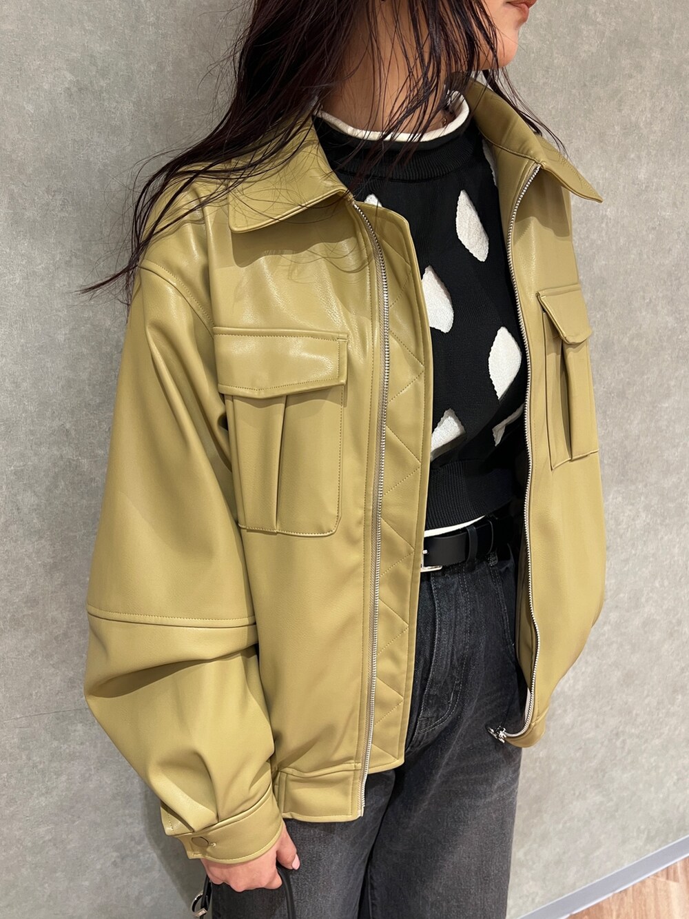 イエロー系のブルゾン、ブラック系のニット/セーター、ブラック系のデニムパンツを着用したレディースの冬コーディネートの4枚目の写真