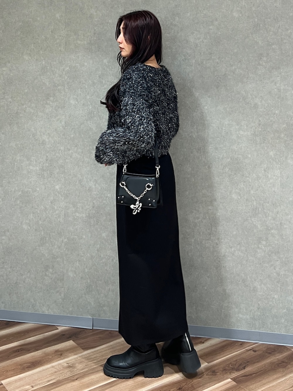 ブラック系のニット/セーター、ブラック系のスカート、ブラック系のブーツを着用したレディースの冬コーディネートの2枚目の写真