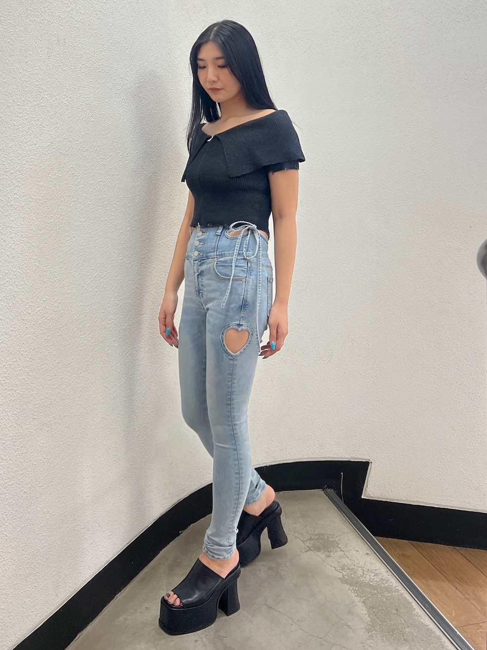 ブラック系のニット/セーター、ブルー系のデニムパンツ、ブラック系のサンダルを着用したレディースの春コーディネートの3枚目の写真