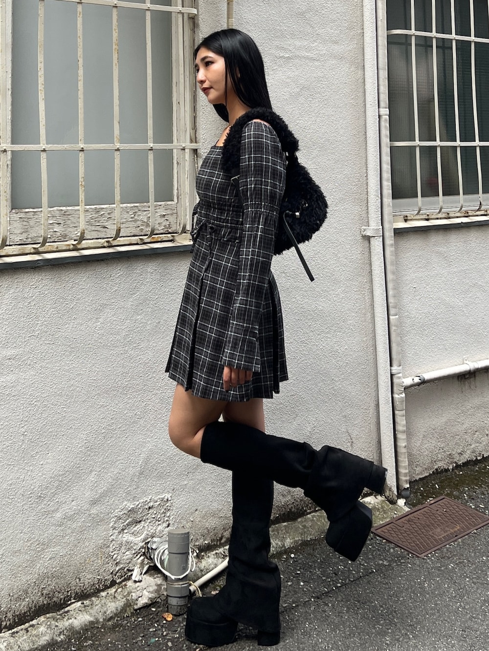 グレー系のワンピース、ブラック系のブーツ、ブラック系のショルダーバッグを着用したレディースの冬コーディネートの2枚目の写真