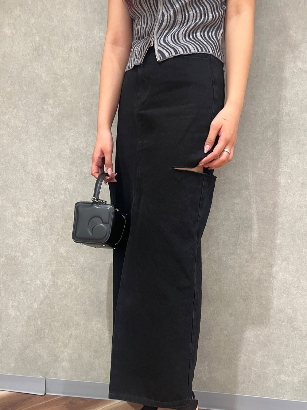 グレー系のタンクトップ、ブラック系のデニムスカート、ブラック系のハンドバッグを着用したレディースの夏コーディネートの7枚目の写真