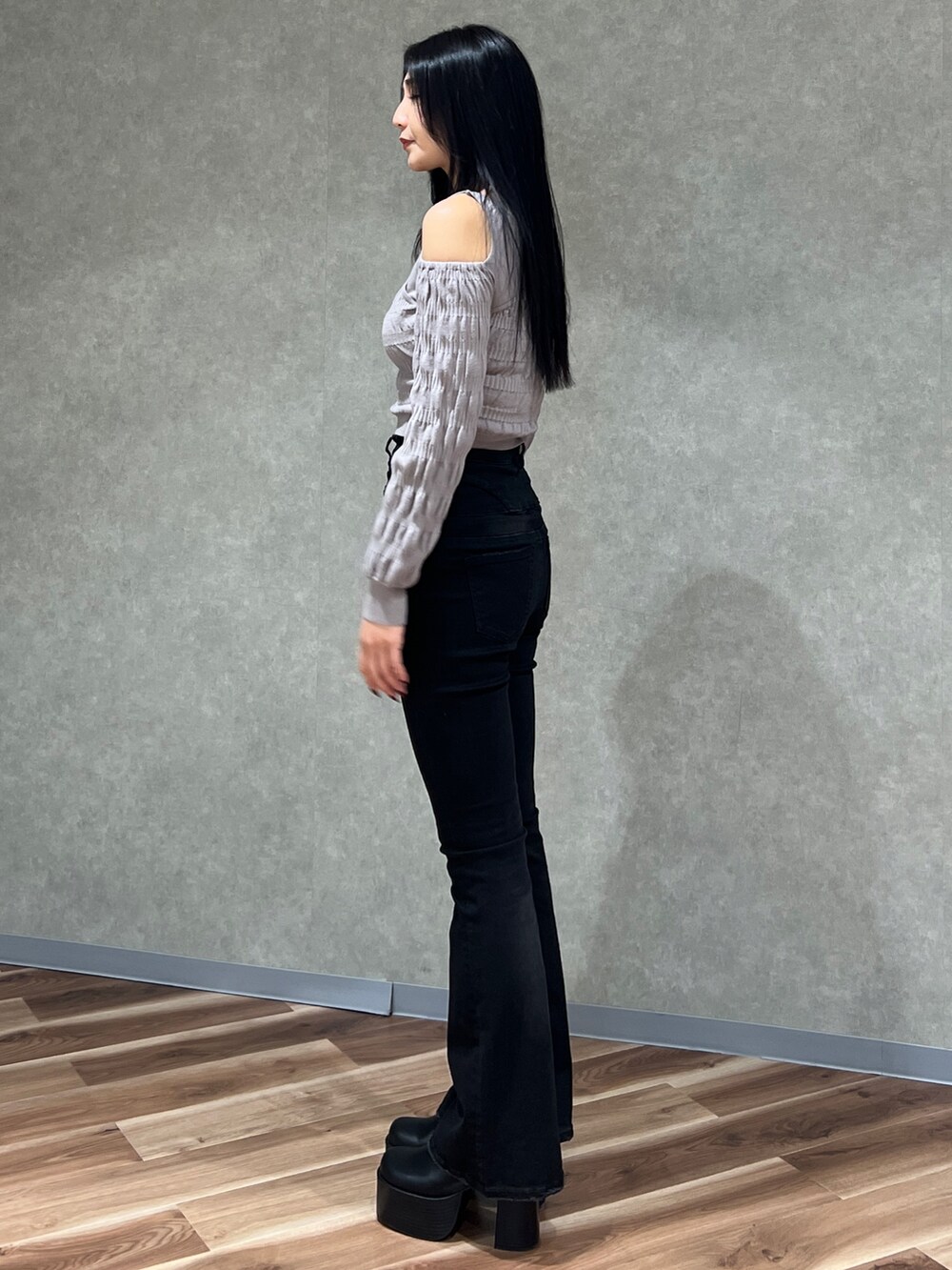 グレー系のニット/セーター、ブラック系のブーツ、ブラック系のデニムパンツを着用したレディースの春コーディネートの2枚目の写真