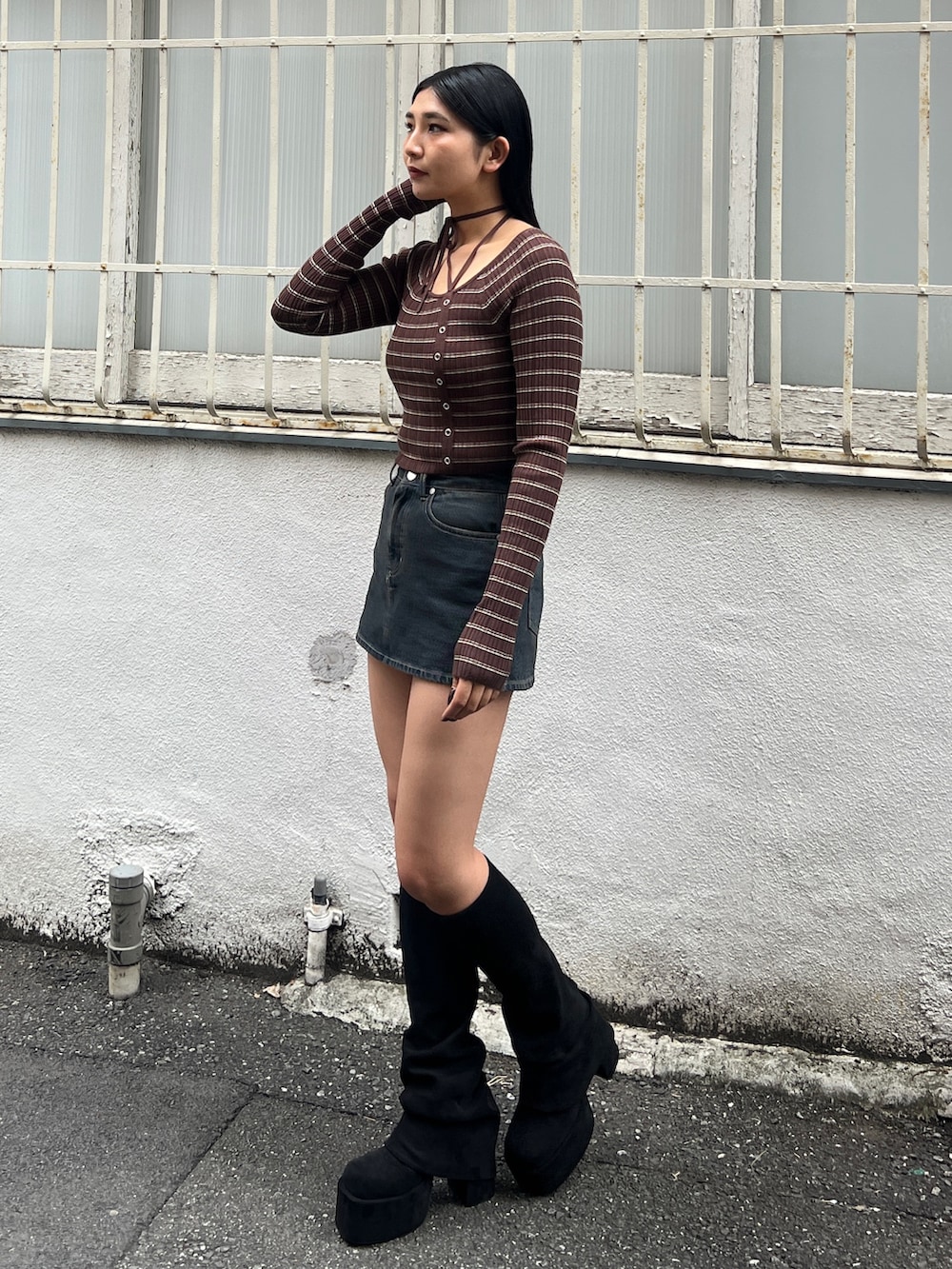 ブラウン系のニット/セーター、ブルー系のスカート、ブラック系のブーツを着用したレディースの冬コーディネートの3枚目の写真