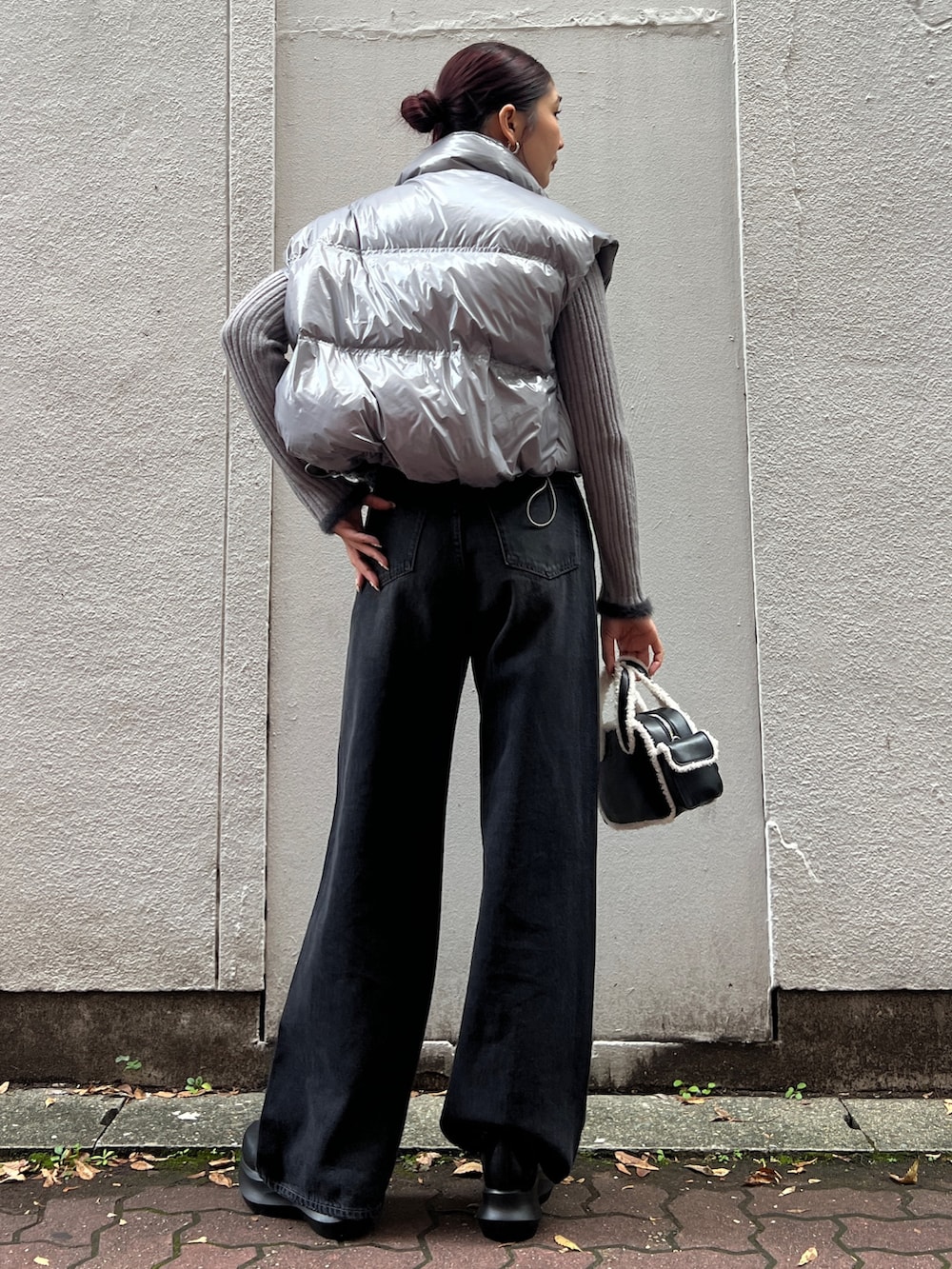 ブラック系のブーツ、ブラック系のハンドバッグ、グレー系のダウンベストを着用したレディースの秋コーディネートの3枚目の写真