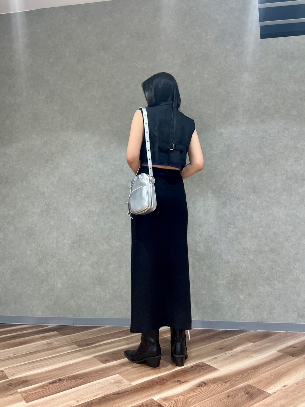 ブラック系のスカート、シルバー系のショルダーバッグ、ブラック系のブーツを着用したレディースの夏コーディネートの5枚目の写真