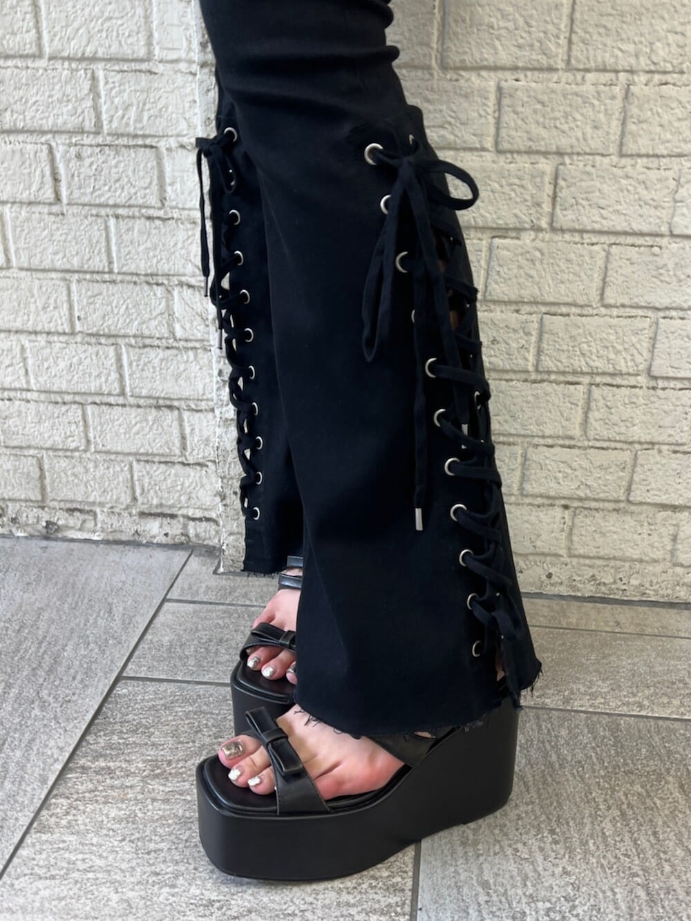 ブラック系のタンクトップ、ブラック系のデニムパンツ、ブラック系のサンダルを着用したレディースの夏コーディネートの5枚目の写真