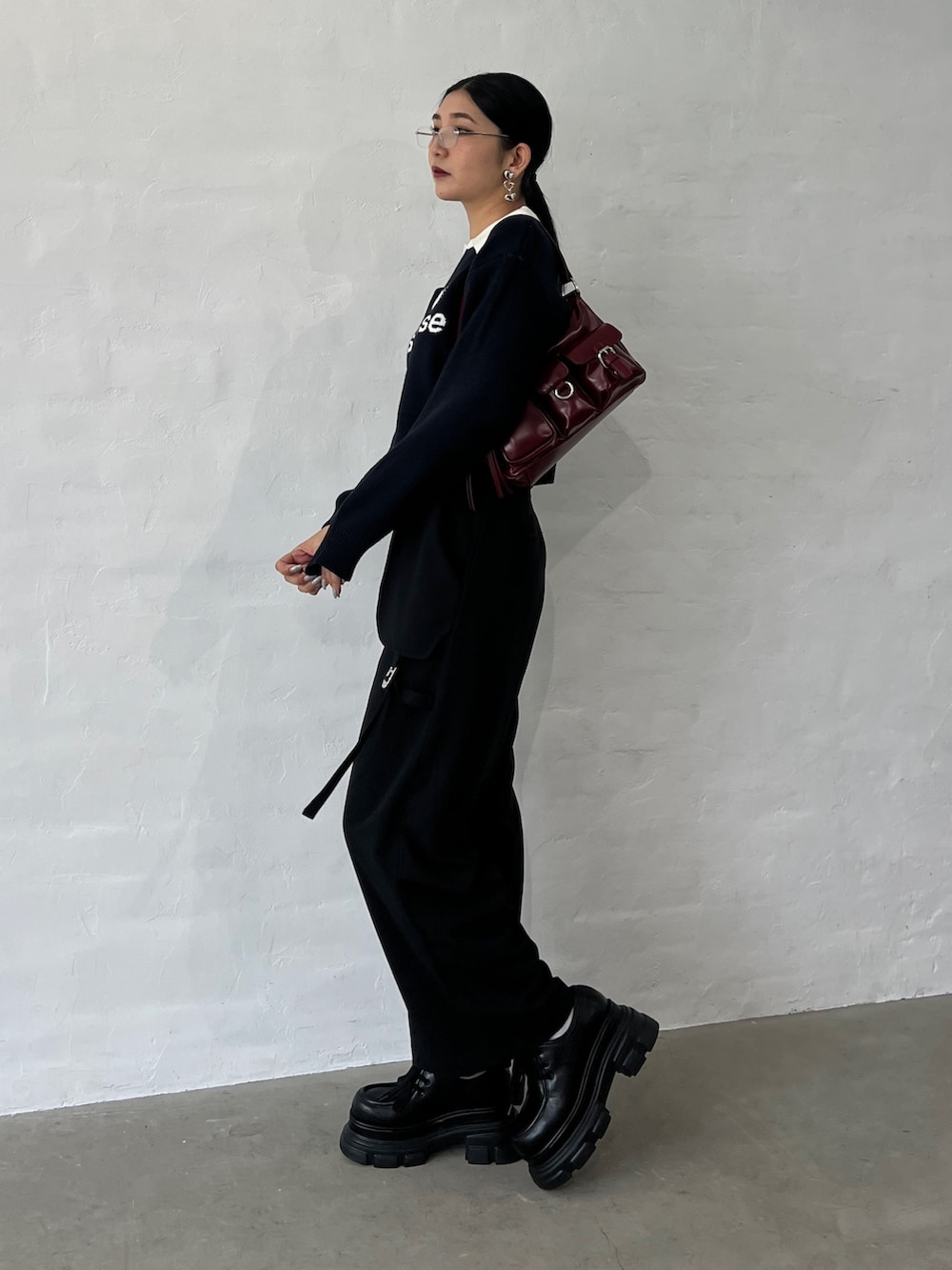 ブラック系のニット/セーター、ブラック系のその他パンツ、レッド系のハンドバッグを着用したレディースの秋コーディネートの2枚目の写真