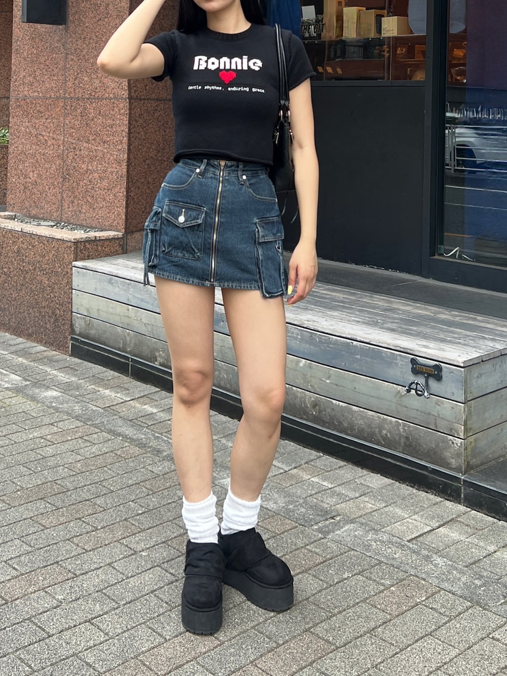 ブラック系のニット/セーター、ブルー系のスカート、ブラック系のその他シューズを着用したレディースの春コーディネートの2枚目の写真