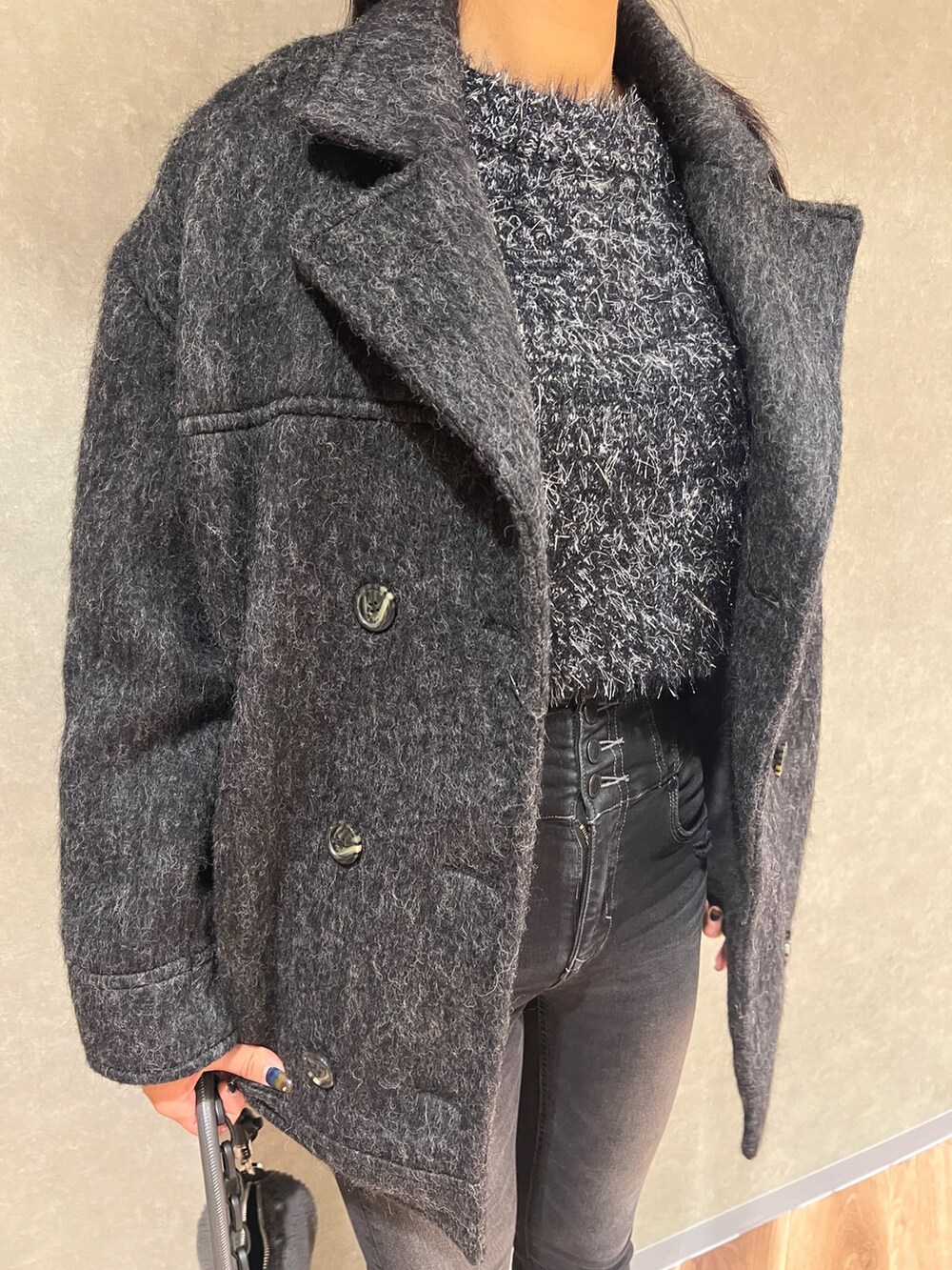 グレー系のピーコート、ブラック系のニット/セーター、ブラック系のデニムパンツを着用したレディースの秋コーディネートの4枚目の写真