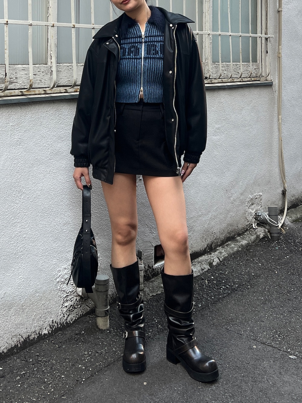 ブラック系のブルゾン、ブラック系のスカート、ブラック系のブーツを着用したレディースの冬コーディネートの2枚目の写真