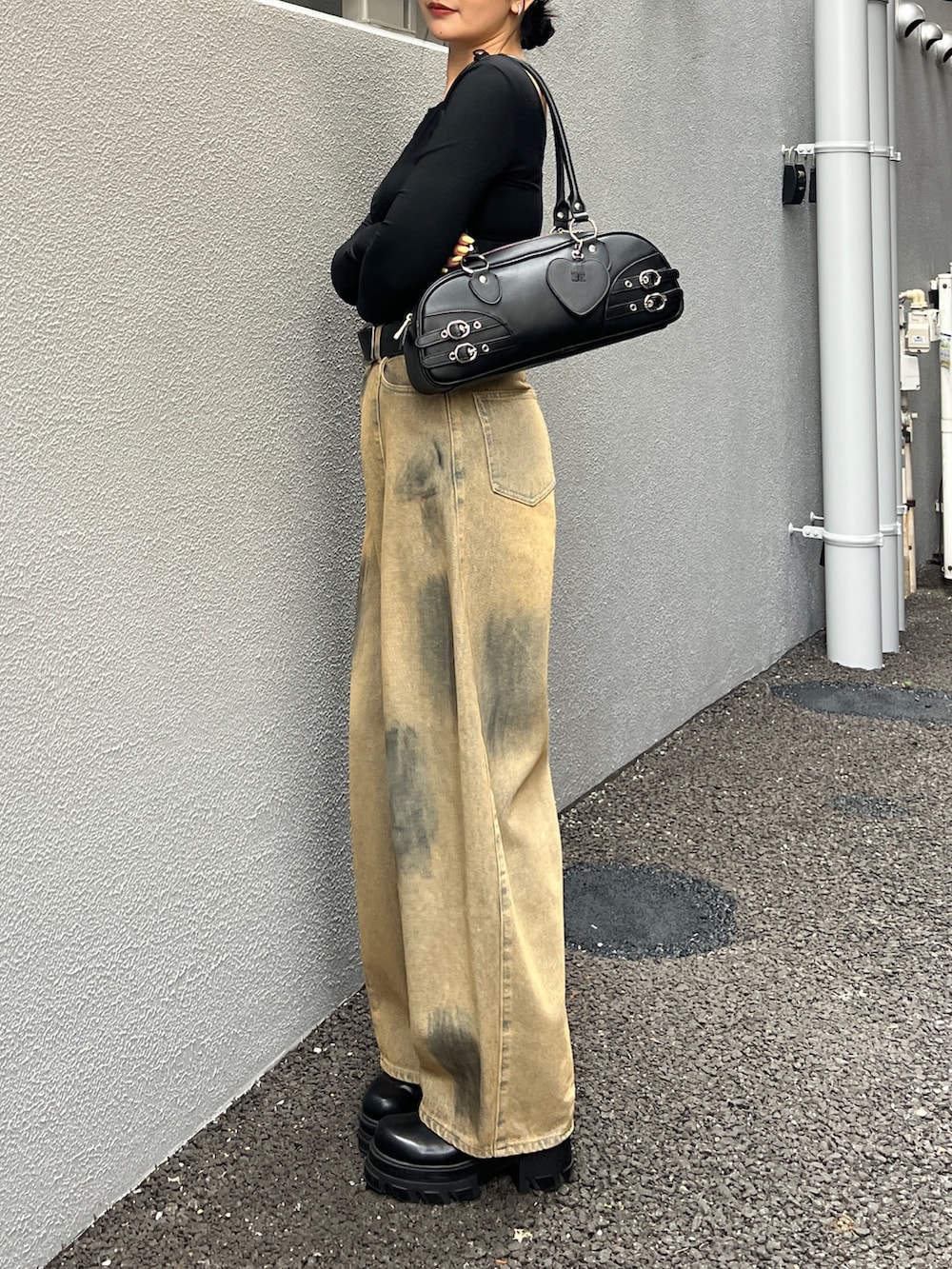 ベージュ系のデニムパンツ、ブラック系のブーツ、ブラック系のハンドバッグを着用したレディースの春コーディネートの2枚目の写真