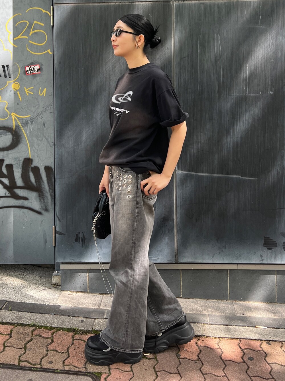 ブラック系のTシャツ/カットソー、ブラック系のスニーカー、ブラック系のハンドバッグを着用したレディースの春コーディネートの2枚目の写真