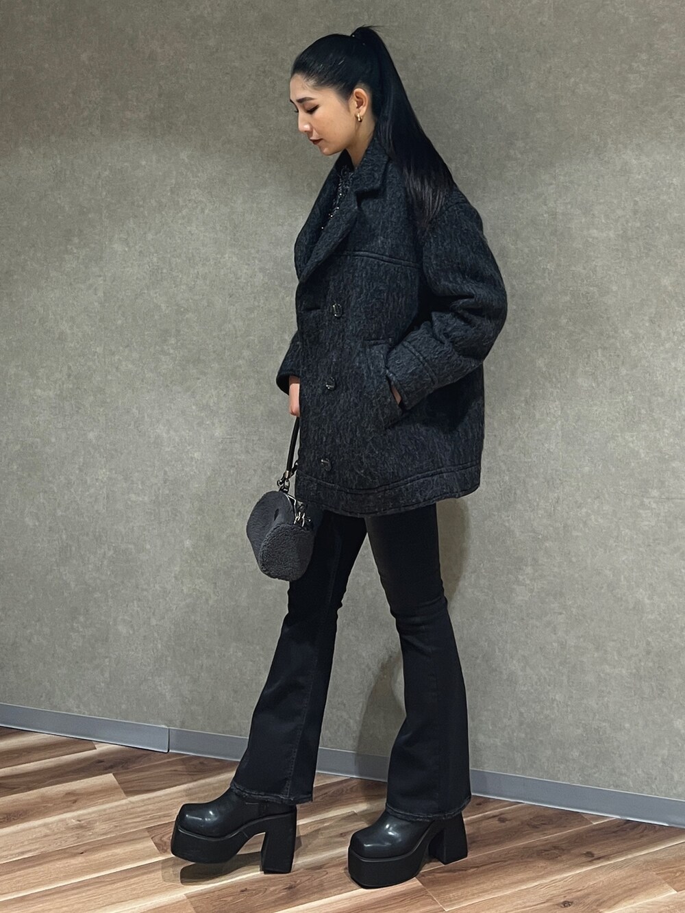 グレー系のピーコート、ブラック系のニット/セーター、ブラック系のデニムパンツを着用したレディースの秋コーディネートの2枚目の写真