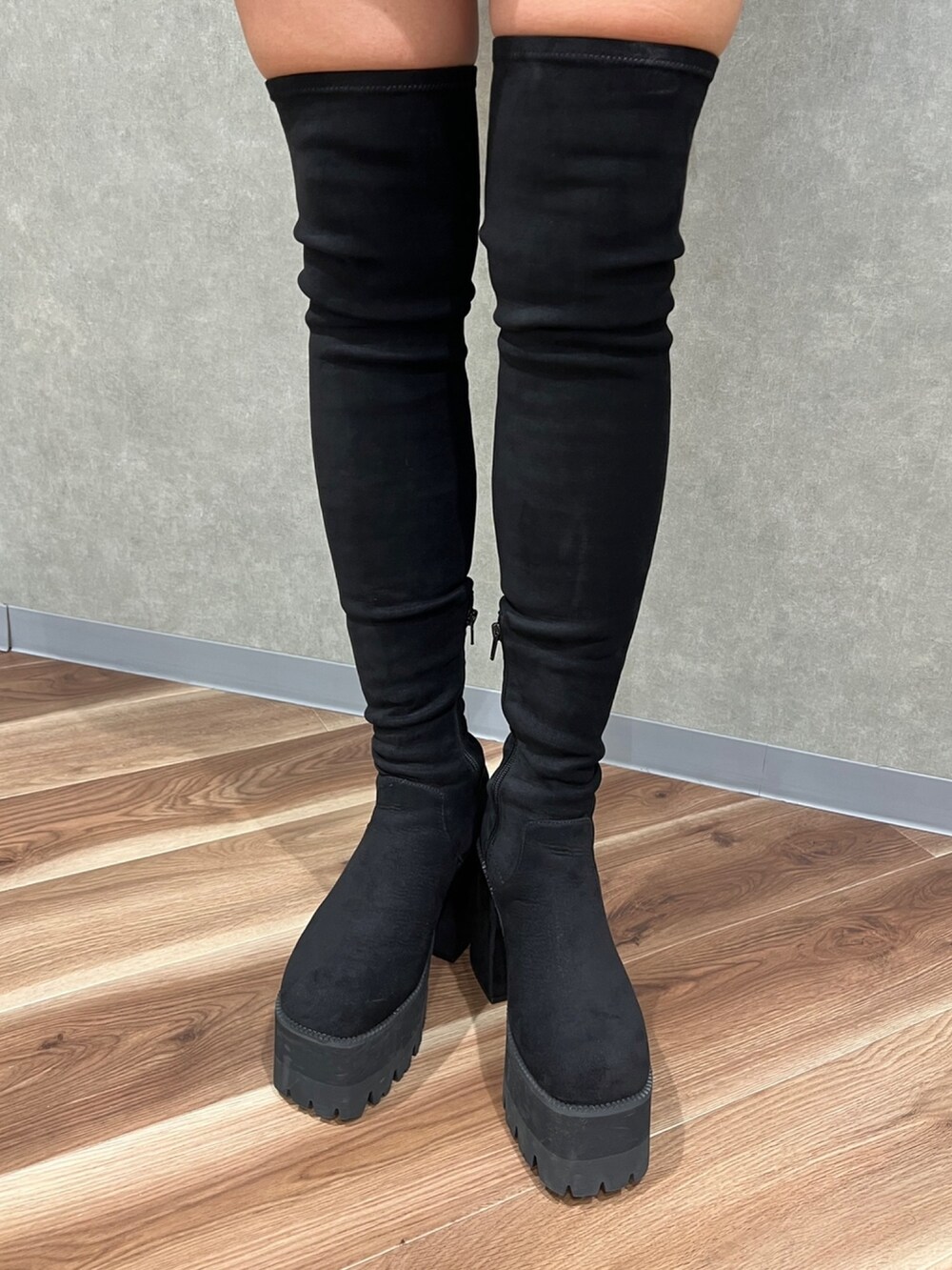 グレー系のニット/セーター、ブラック系のスカート、ブラック系のブーツを着用したレディースの秋コーディネートの6枚目の写真