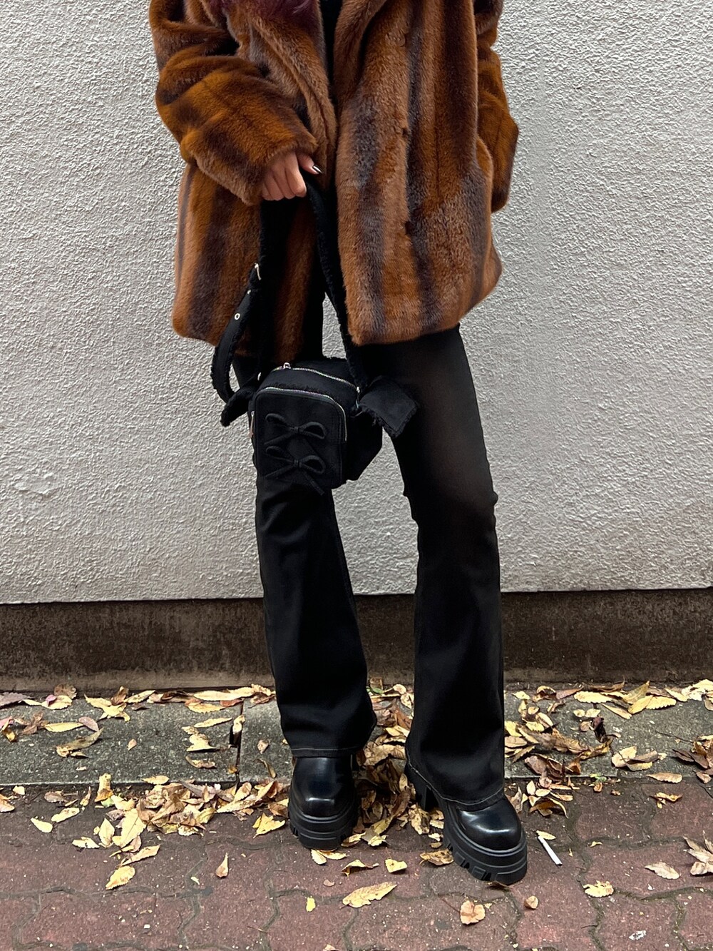 ブラウン系のその他アウター、ブラック系のニット/セーター、ブラック系のデニムパンツを着用したレディースの冬コーディネートの5枚目の写真