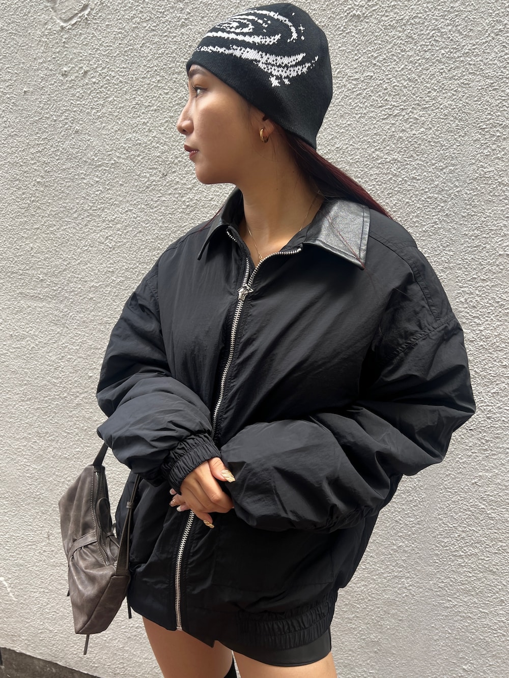 ホワイト系のキャミソール、ブラック系のブルゾン、ブラック系のその他パンツを着用したレディースの秋コーディネートの4枚目の写真