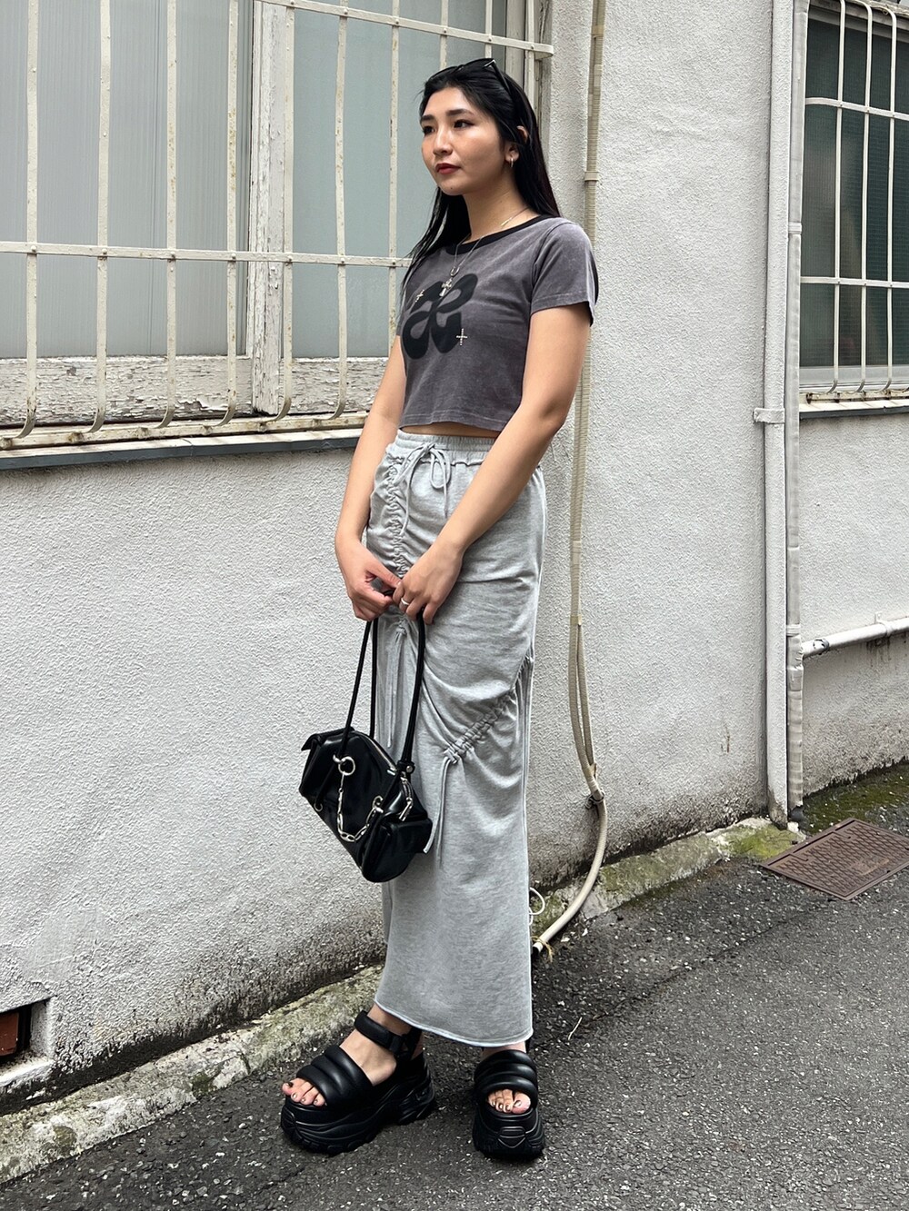 グレー系のTシャツ/カットソー、グレー系のスカート、ブラック系のサンダルを着用したレディースの夏コーディネートの2枚目の写真