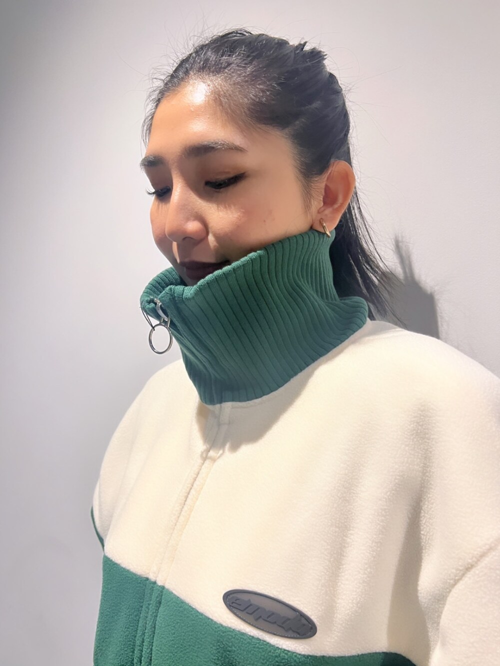 グリーン系のブルゾン、ブラック系のスカート、ブラック系のブーツを着用したレディースの秋コーディネートの4枚目の写真