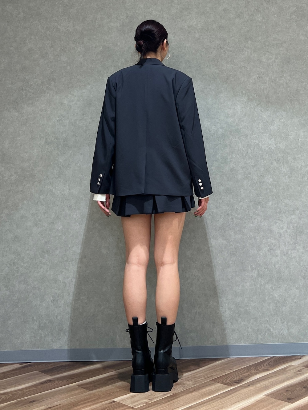 グレー系のテーラードジャケット、ホワイト系のニット/セーター、グレー系のスカートを着用したレディースの冬コーディネートの3枚目の写真